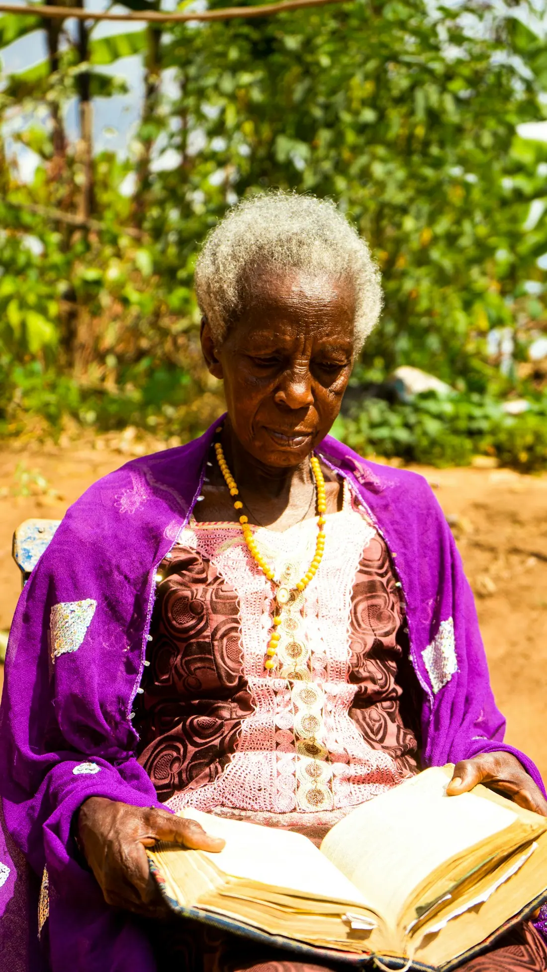 An older woman reading in a garden